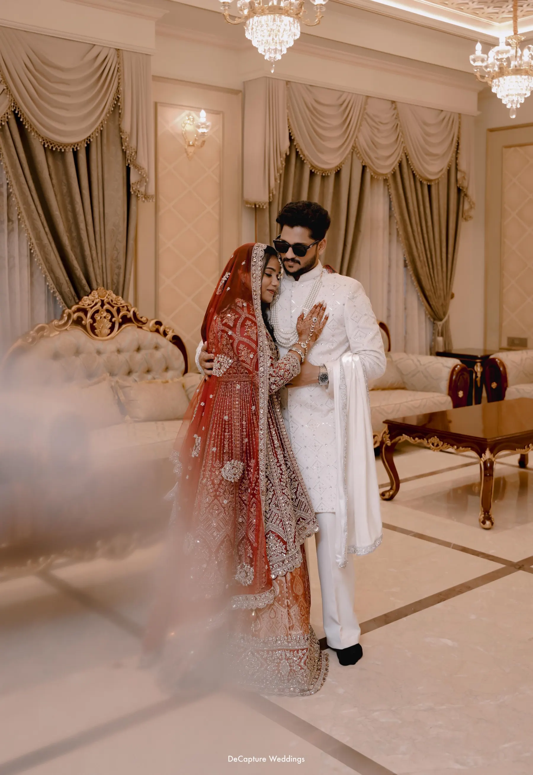 Ashhar and Mufeeda standing closely together in an elegant warm-toned setting.